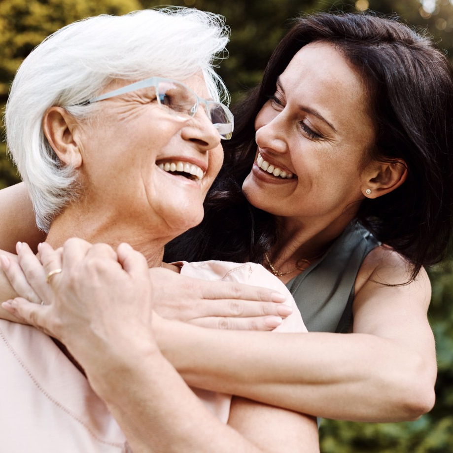 Older woman with younger woman smiling in embrace